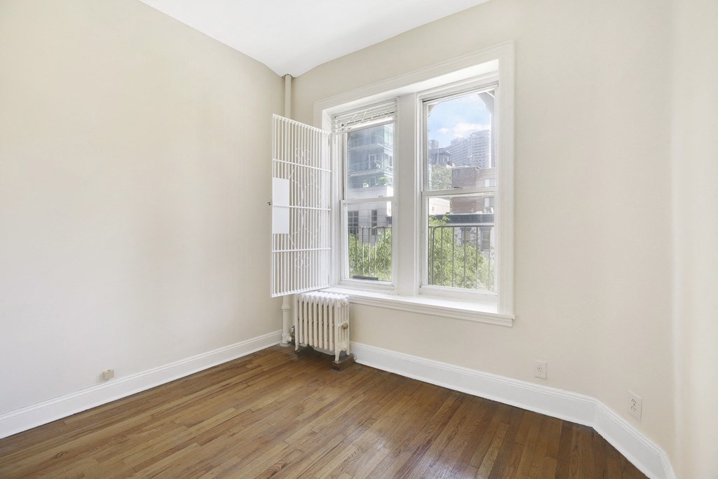an empty room with a window and a radiator and a cage on the wall