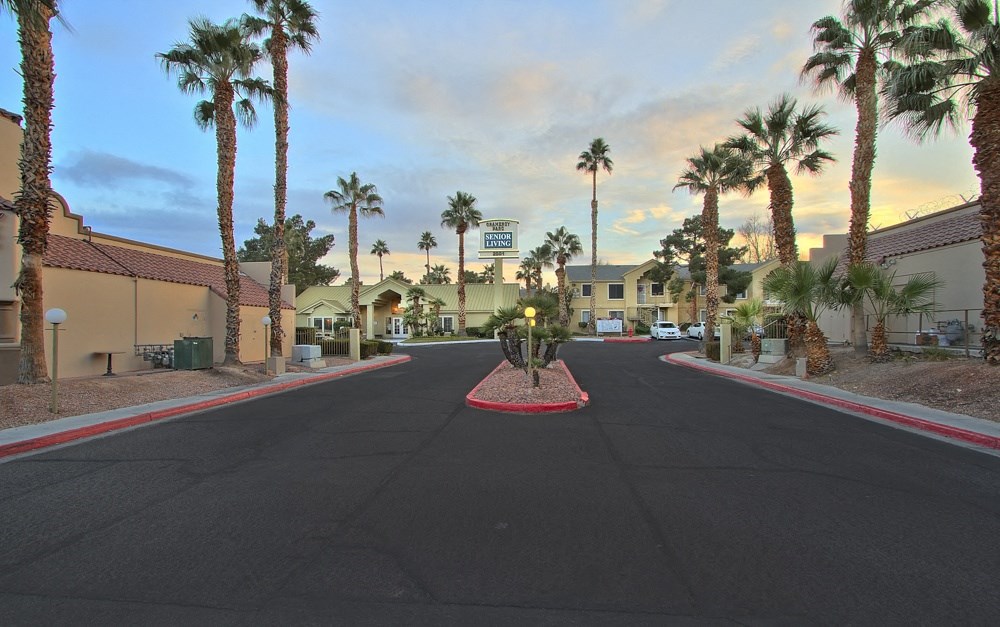 an empty street with palm trees in front of a hotel