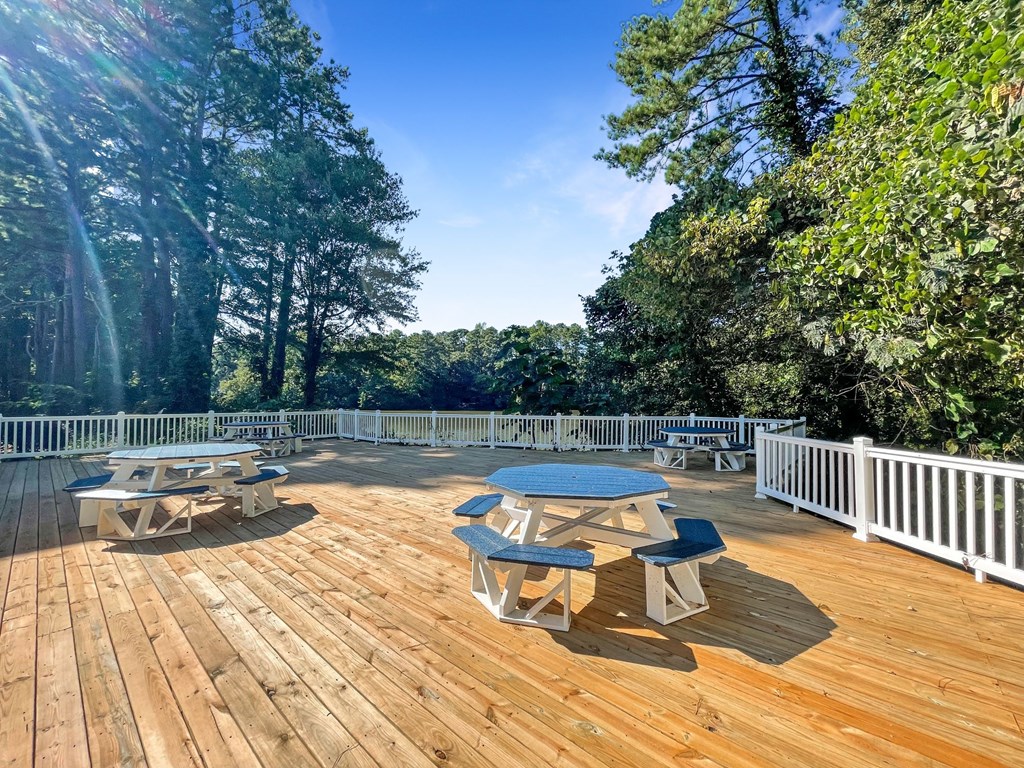 1 Park Central Apartments, Peachtree Corners, Georgia a large deck with picnic tables and a view of the trees