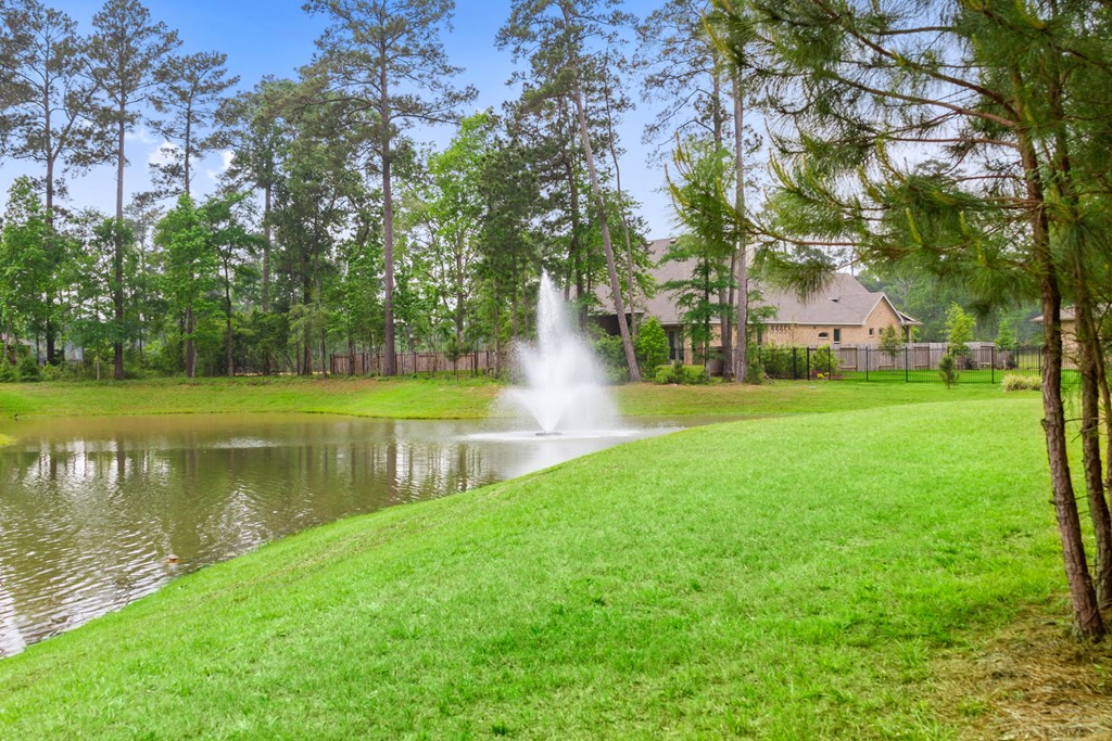 a fountain in a pond with a house in the background