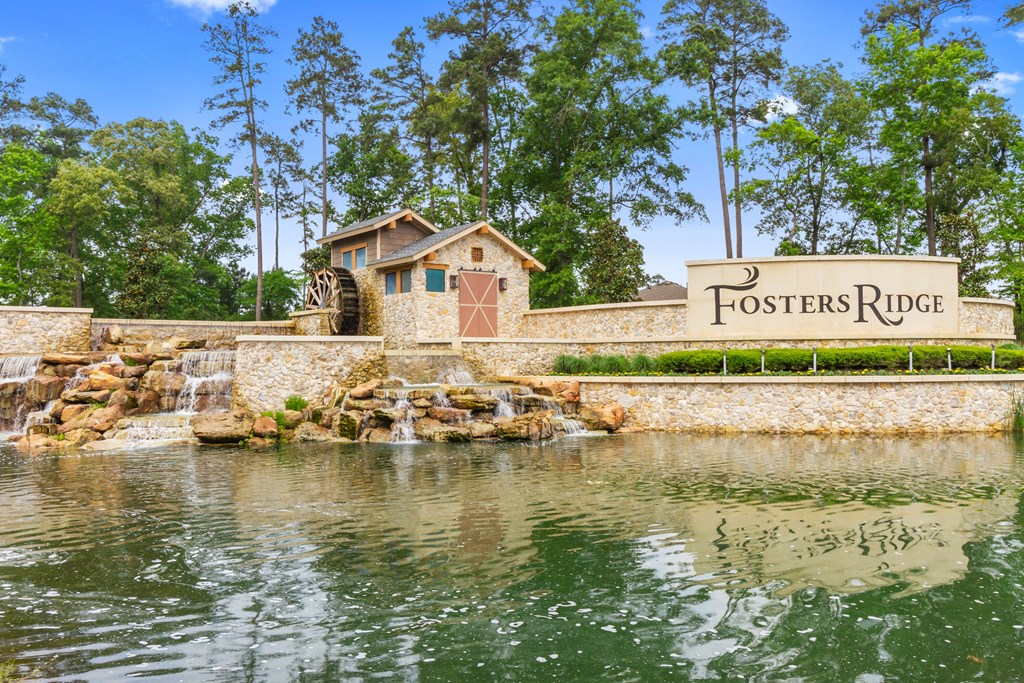 a stone retaining wall with a sign that reads fosters ridge and a water feature with a