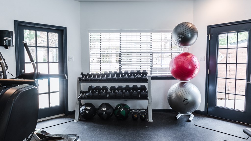 a gym with weights and balls and a window
