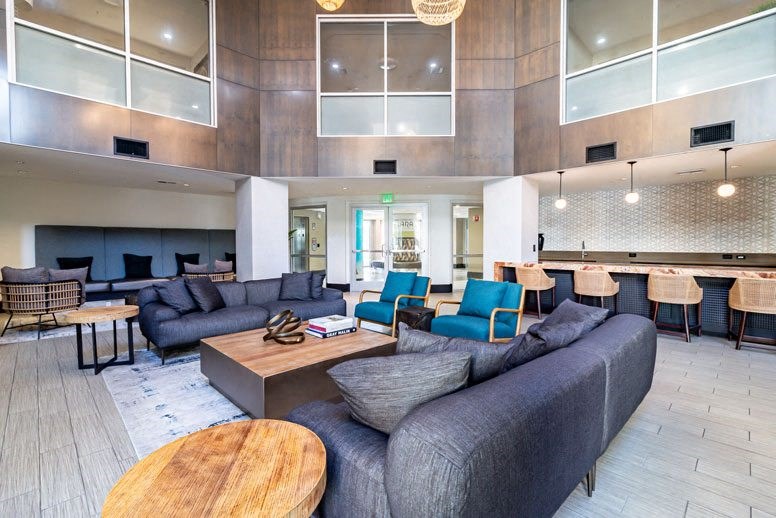 a lobby with couches tables and chairs and a kitchen