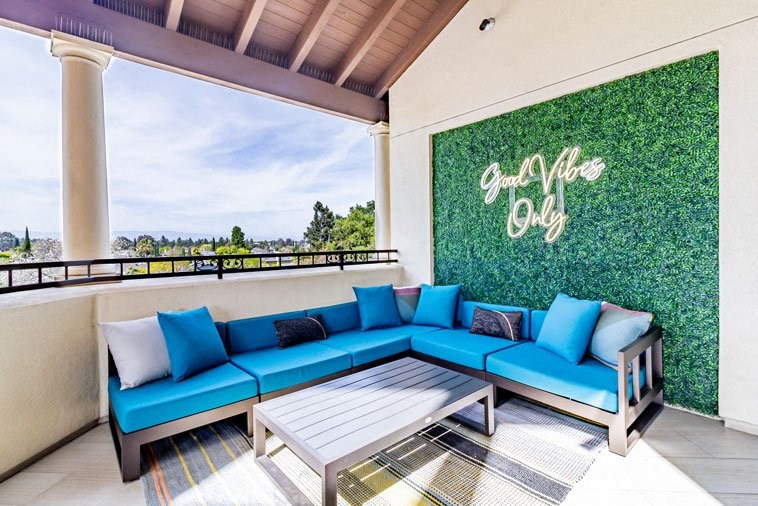 a patio with blue couches and a table and a green wall