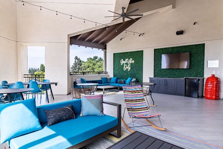 a patio with blue couches and chairs and tables and a tv