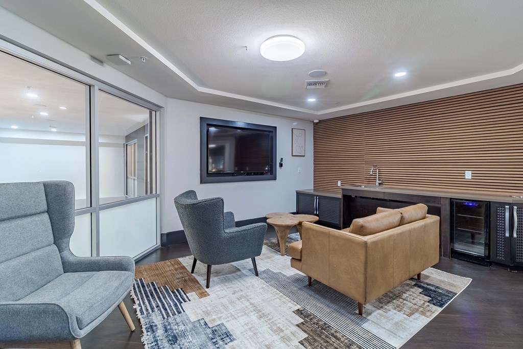 A modern living room with a grey sofa, a grey armchair, a brown sofa, a wooden coffee table, and a TV mounted on the wall.