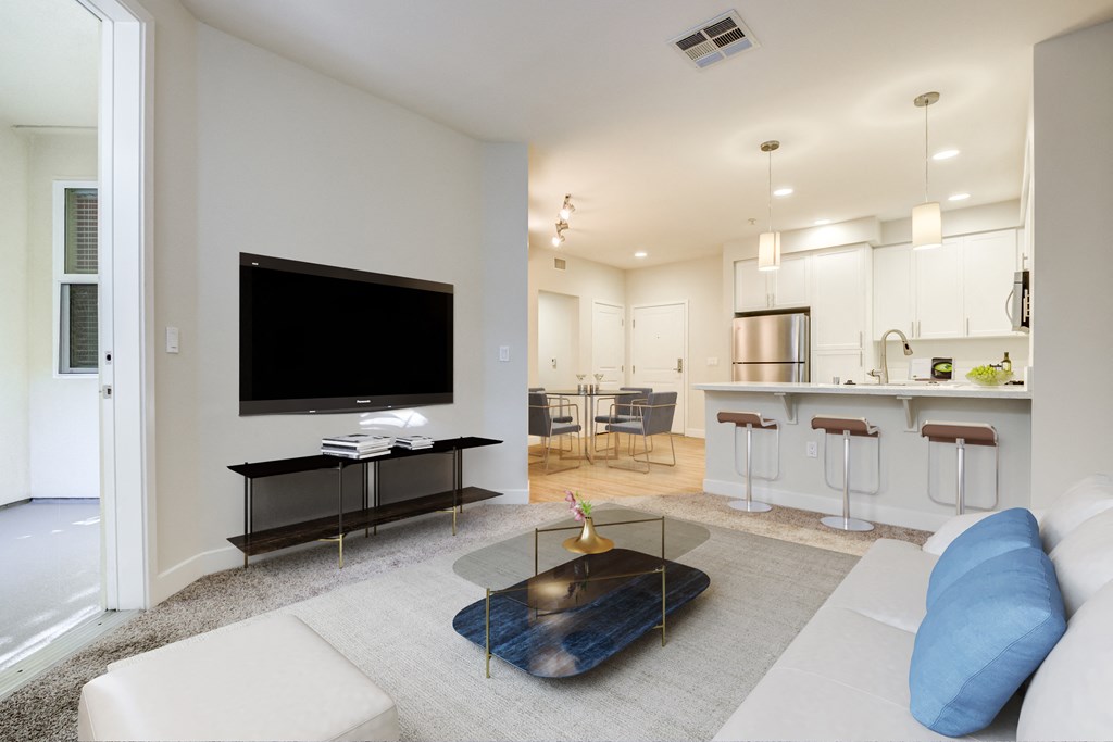 A modern living room with a flat screen TV and a bar area.