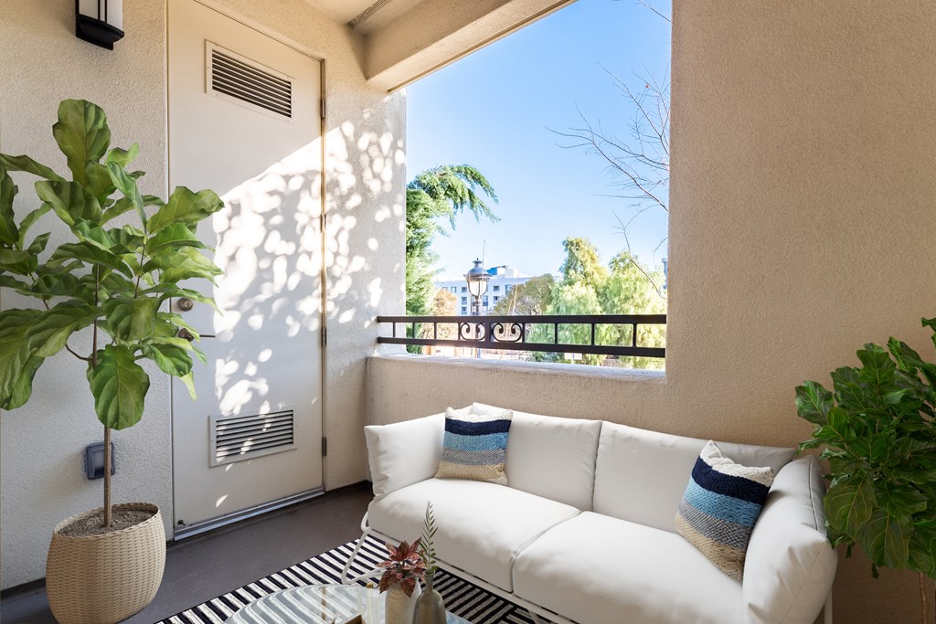 A white couch with blue and white pillows sits in a room with a large window.