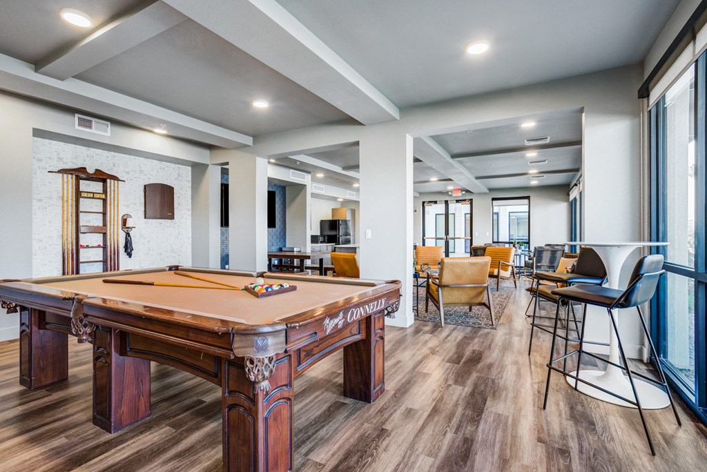 Luxury Apartments Downtown Phoenix, AZ - Imperial Apartments - Clubhouse with Pool Table, Mounted TV, Wood-Style Flooring, Tables, Chairs, and High Ceilings.