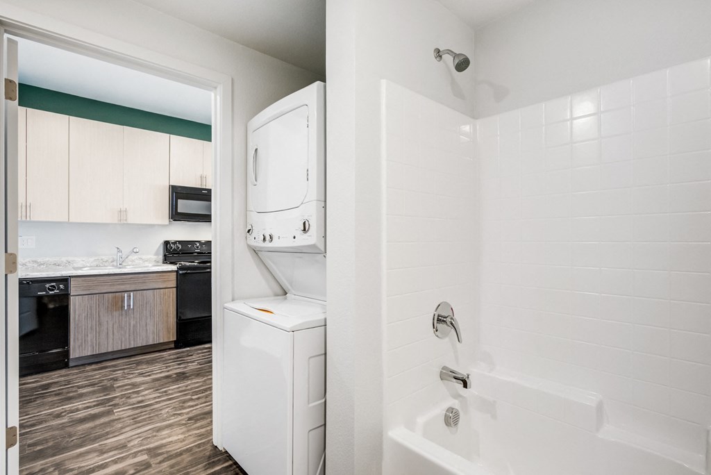Apartments for Rent in Phoenix, AZ - Imperial - Laundry Closet Inside Bathroom with Stacked Washer and Dryer, Shower and Tub, and View of Kitchen.