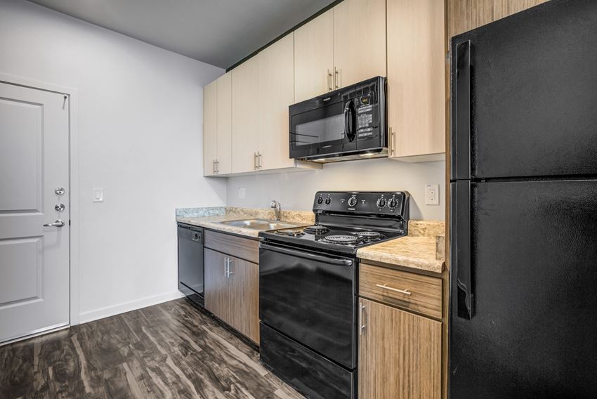 Apartments for Rent Phoenix, AZ - Large Kitchen with Black Appliances, Wood Flooring, and Brown Cabinetry - Photo Gallery 1
