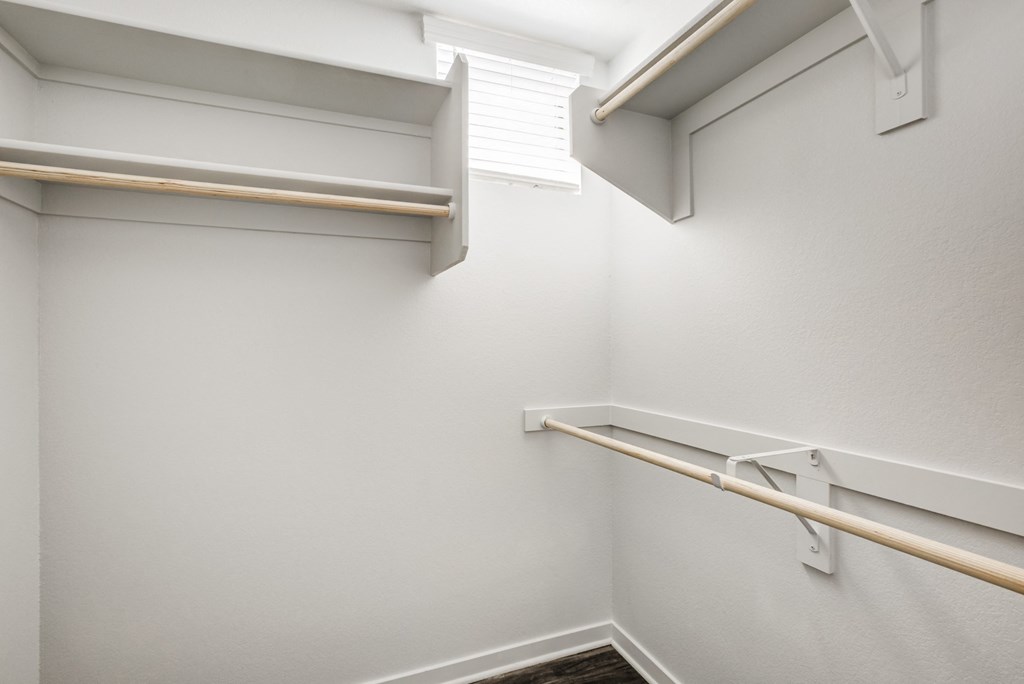 Apartments for Rent in Phoenix, AZ - Imperial - Oversized Closet with White Walls, Built-In Shelves, Wooden Rods, and Wood-Style Flooring