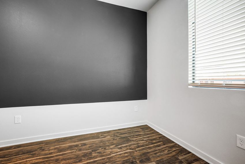 an empty room with a black wall and a window