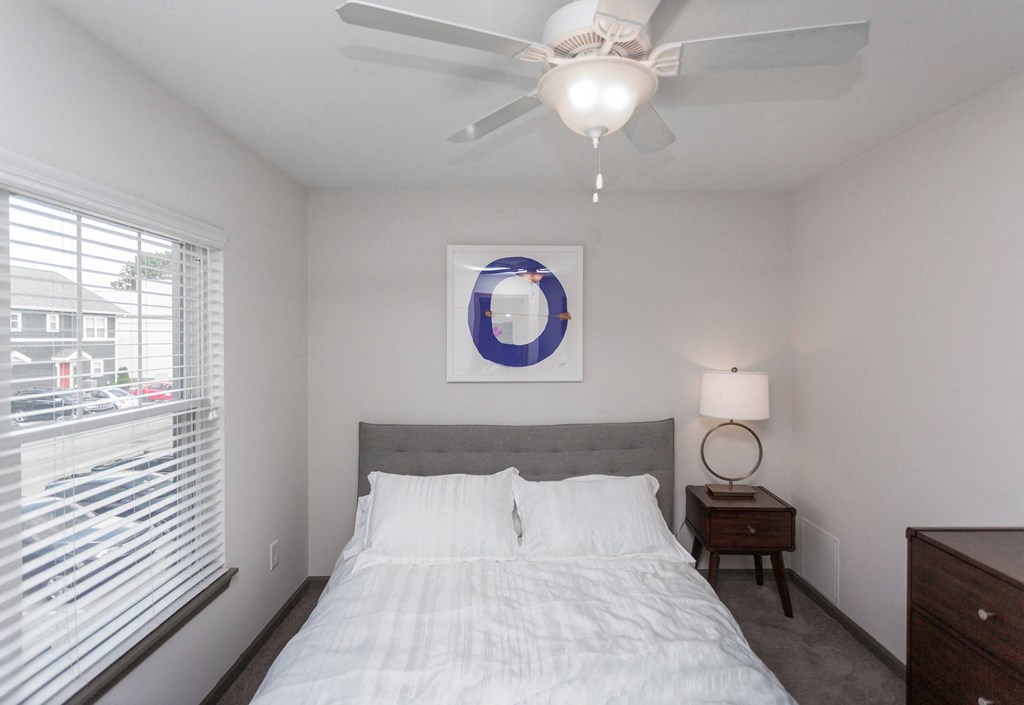 a bedroom with a ceiling fan and a window with blinds
