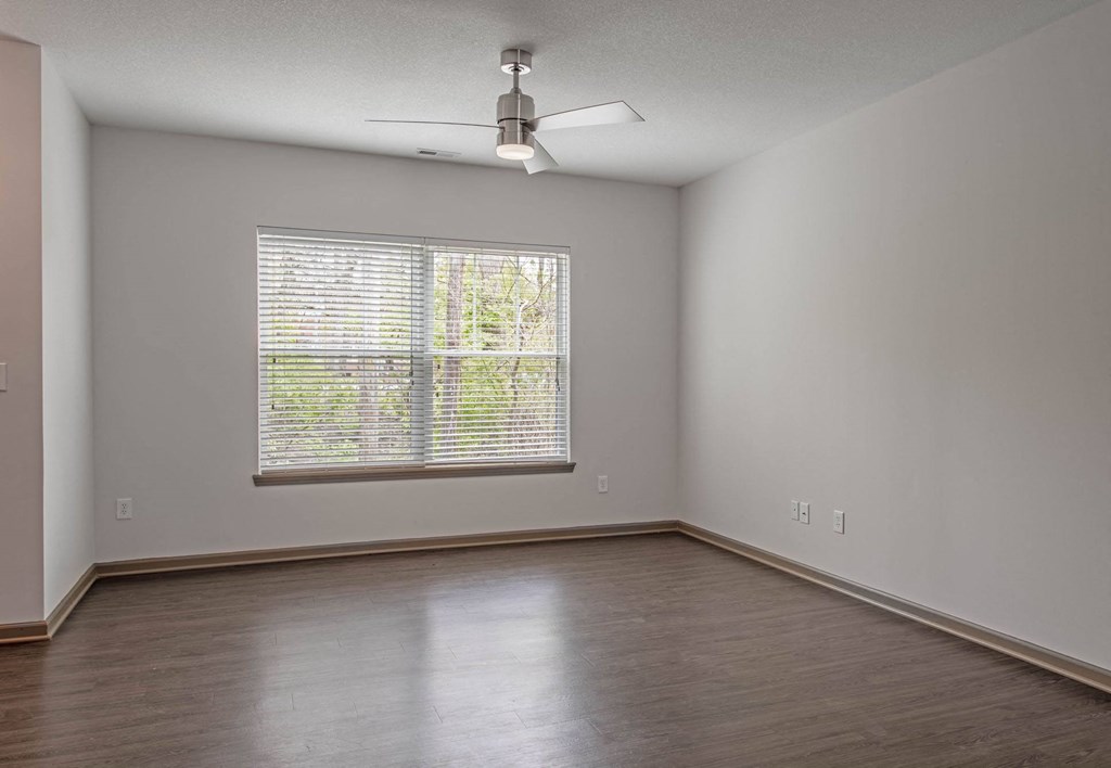 an empty bedroom with a large window and a ceiling fan