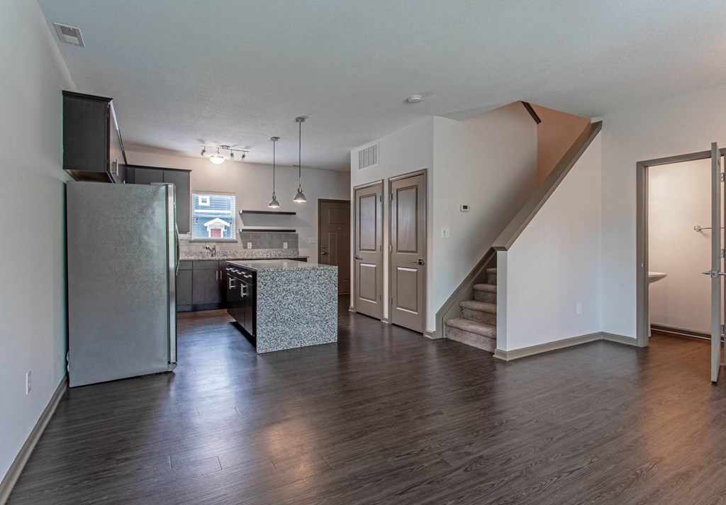 a kitchen and living room with hardwood floors and a staircase