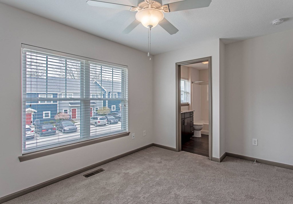 a bedroom with a large window and a ceiling fan