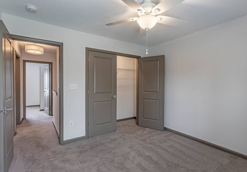 a bedroom with two closets and a ceiling fan