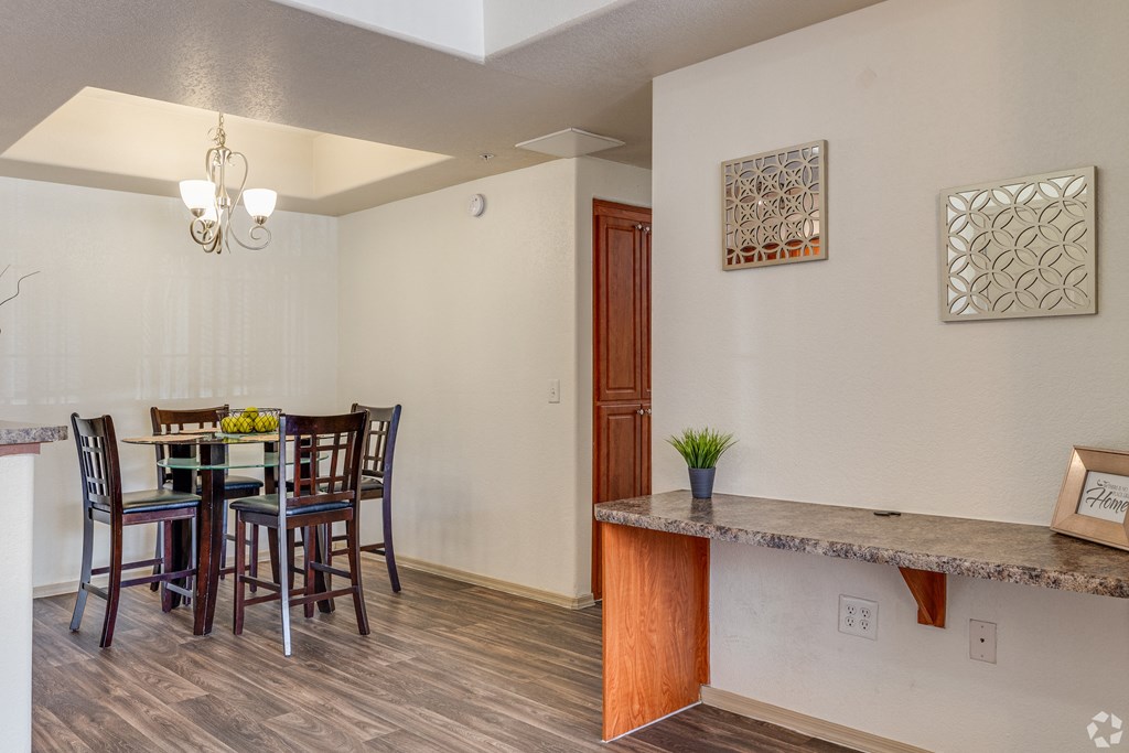 A dining room with a table set for two and a potted plant on the counter.
