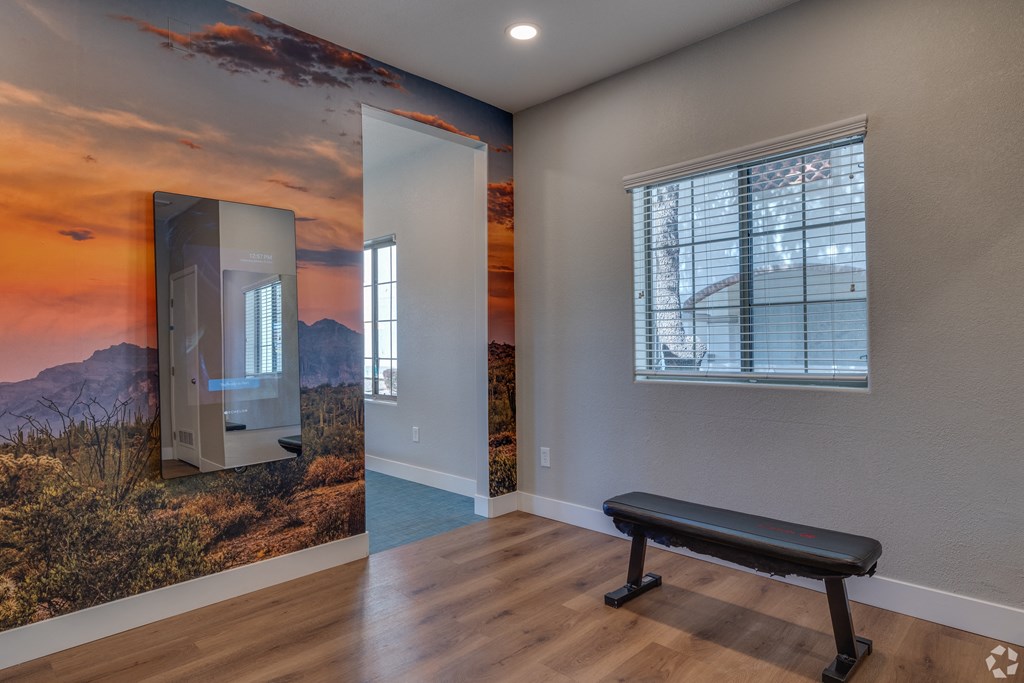 A room with a wall mural of a sunset and a bench.