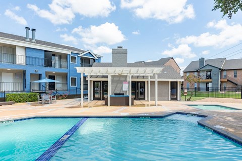 A swimming pool in front of a building with a covered patio area.