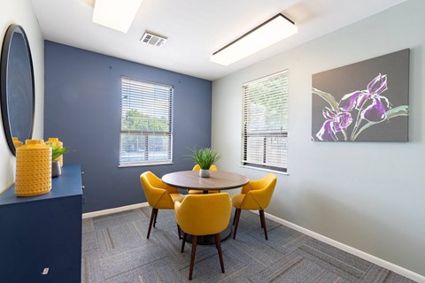 A dining room with a round table and yellow chairs.