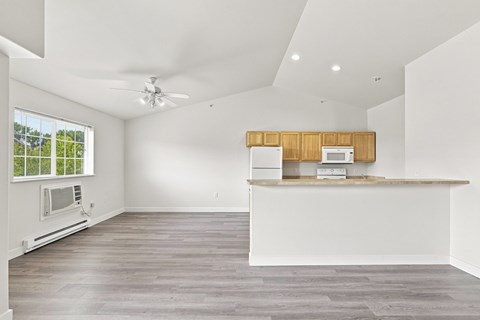 A spacious kitchen with a ceiling fan and a window with blinds.