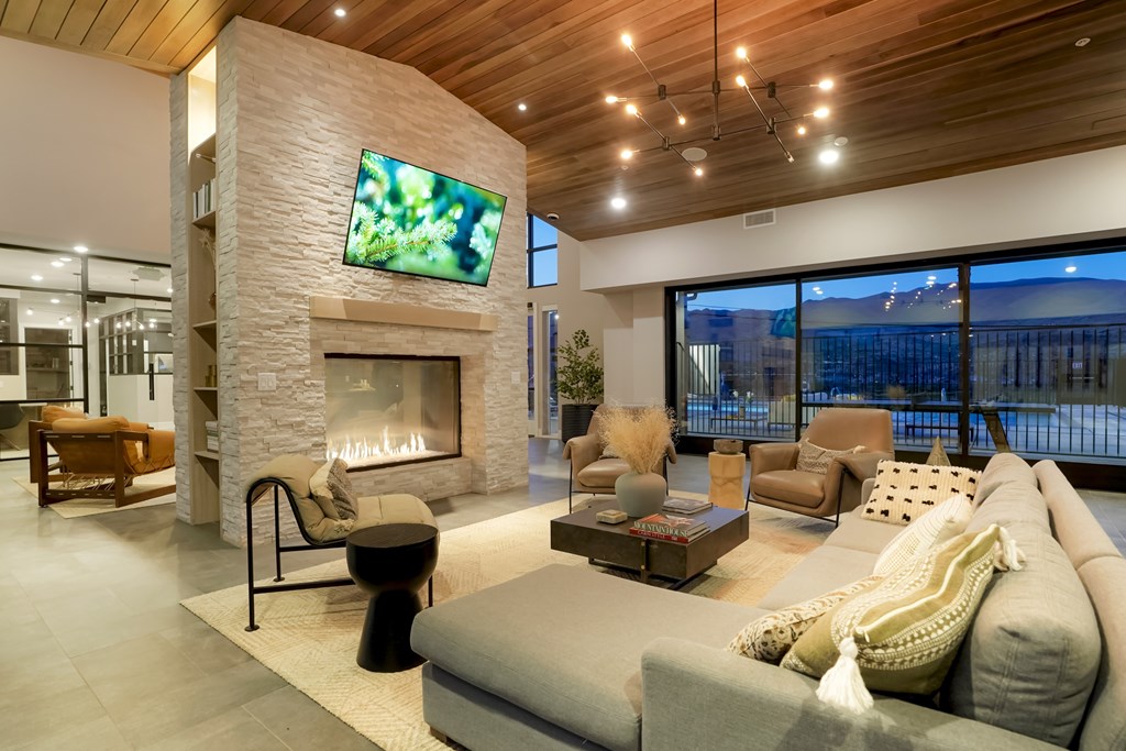 A modern living room with a stone fireplace and a flat screen TV mounted on the wall.