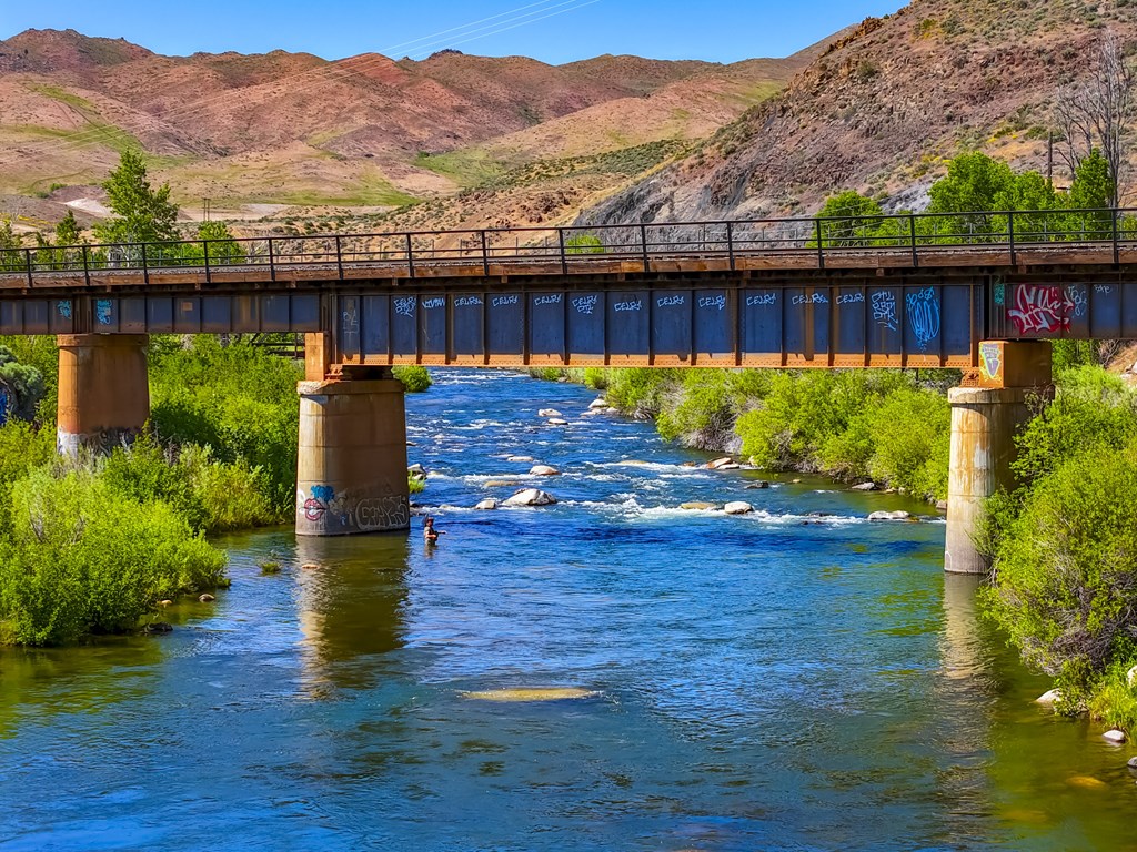 A bridge over a river with a mountain in the background.