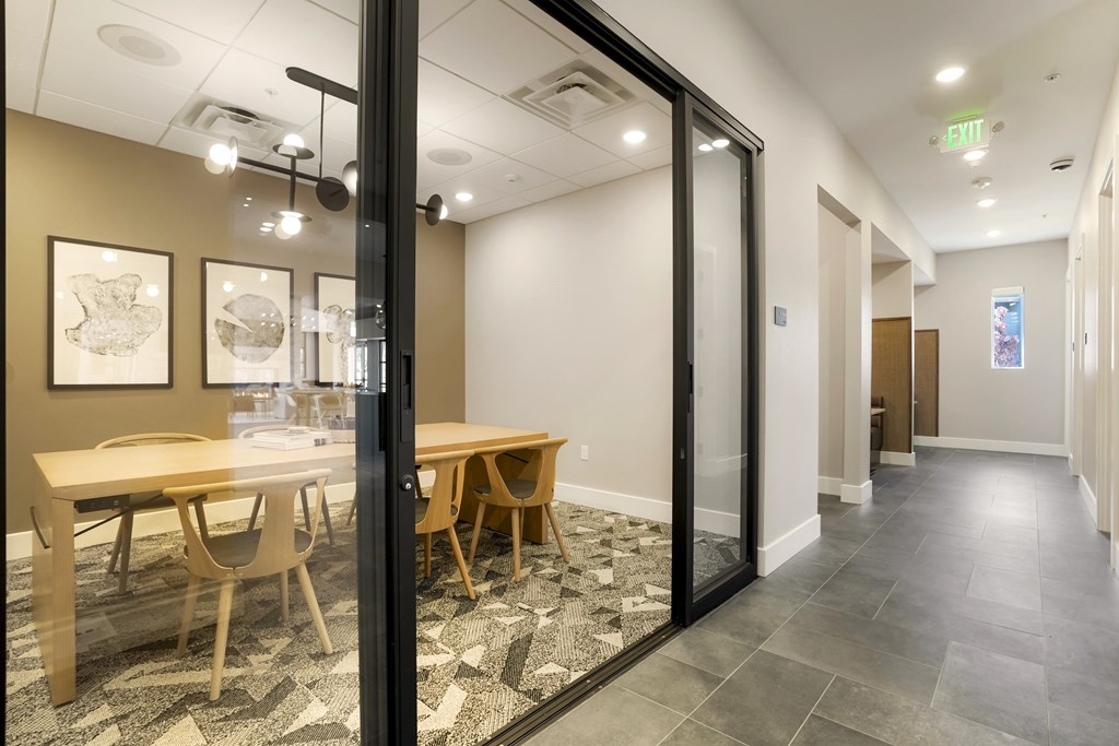 A conference room with a glass door and a table with chairs.