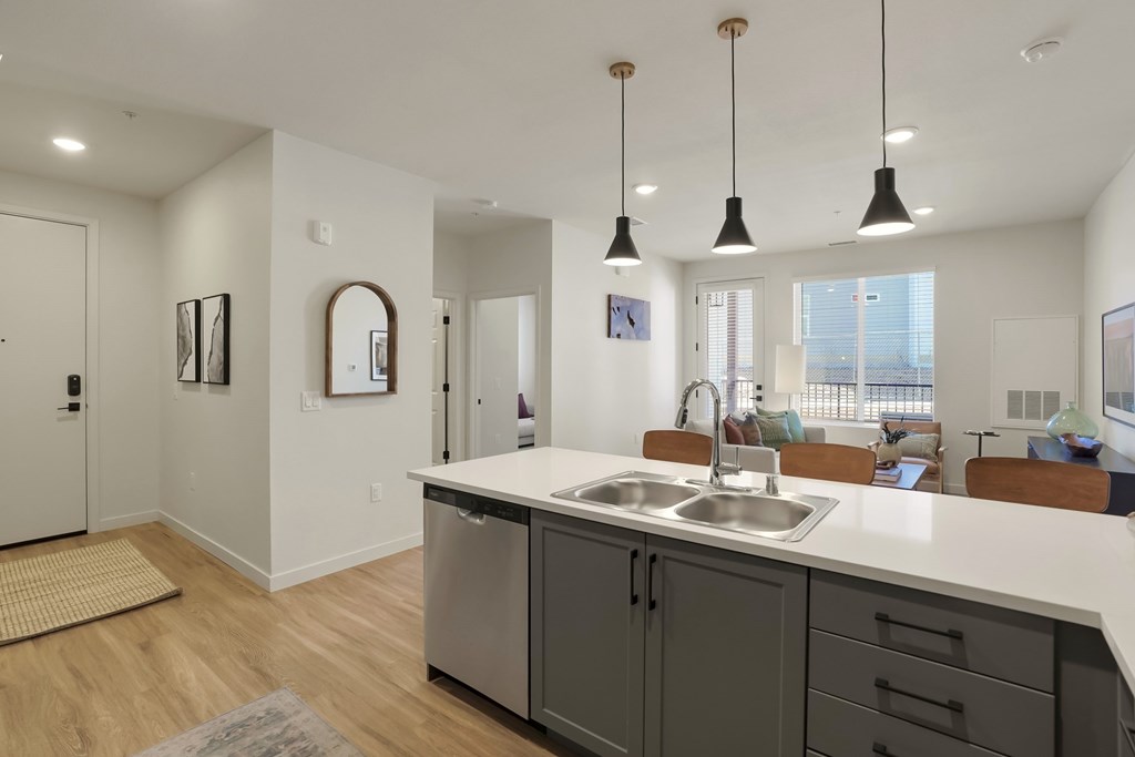 A modern kitchen with a white countertop and grey cabinets.