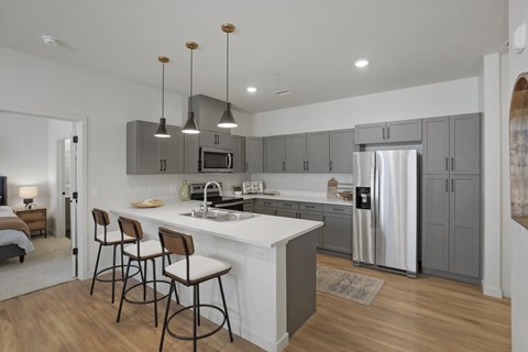 a kitchen with an island with three stools and a stainless steel refrigerator