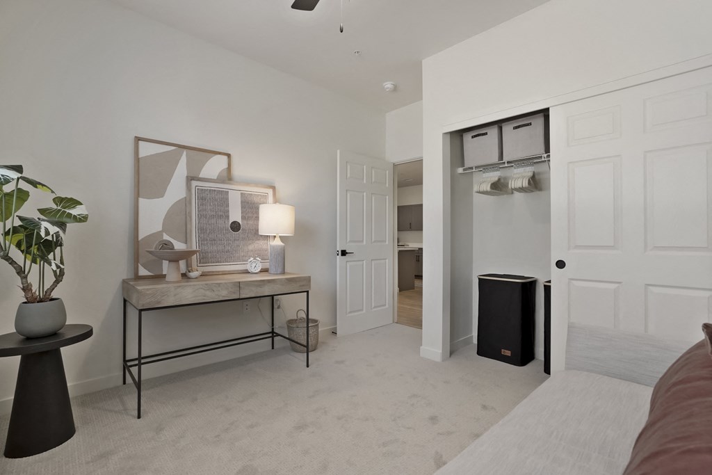 a living room with a desk and a door to a closet