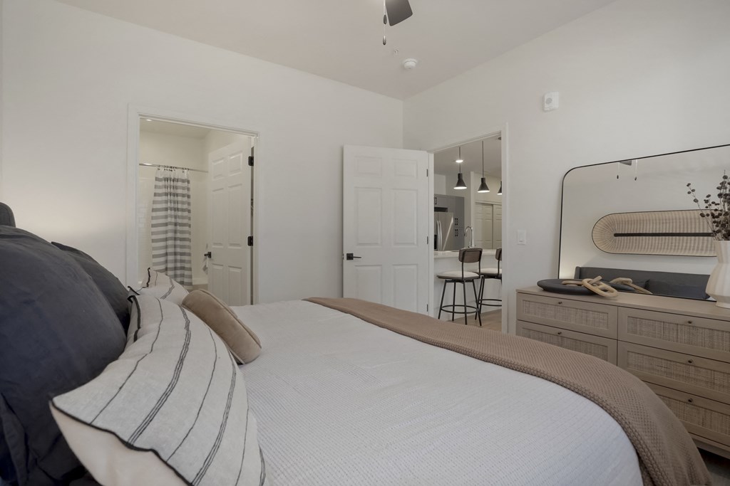 a bedroom with a large bed and a dresser with a mirror