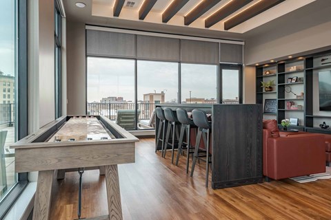 A pool table is in the middle of a room with a bar and a view of the city.