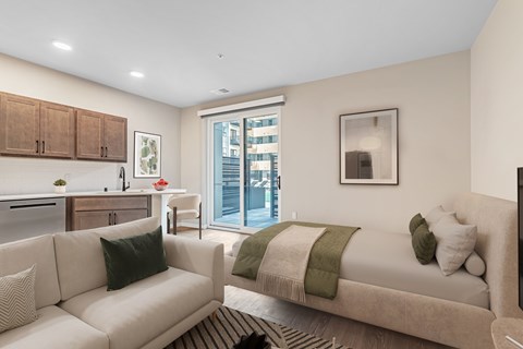 A modern living room with a couch, a bed, and a kitchen area.