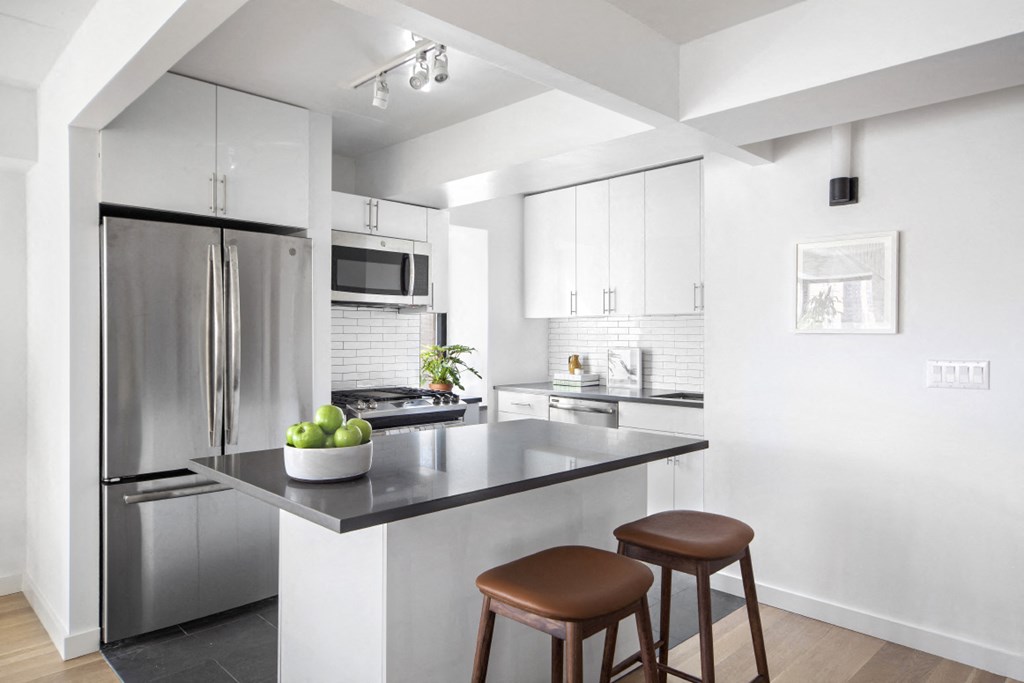 a kitchen with stainless steel appliances and a counter with two stools