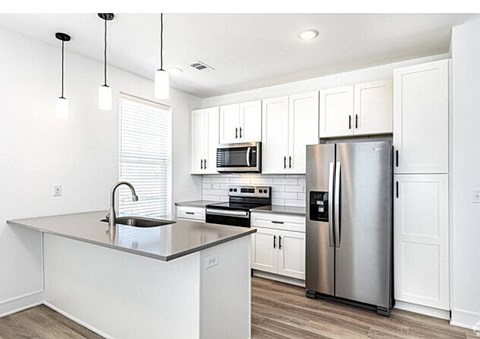 A modern kitchen with a stainless steel refrigerator and white cabinets.