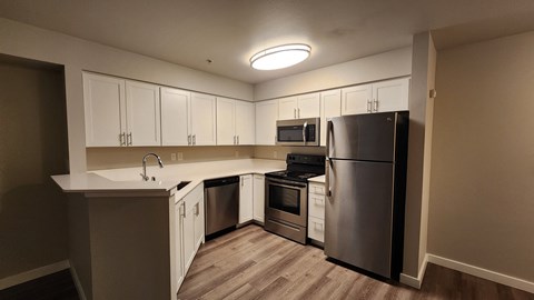 A kitchen with a refrigerator, oven, and microwave.