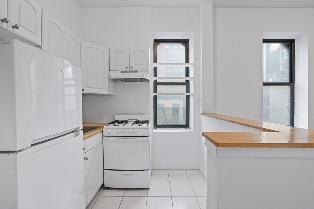 an empty kitchen with white appliances and a window