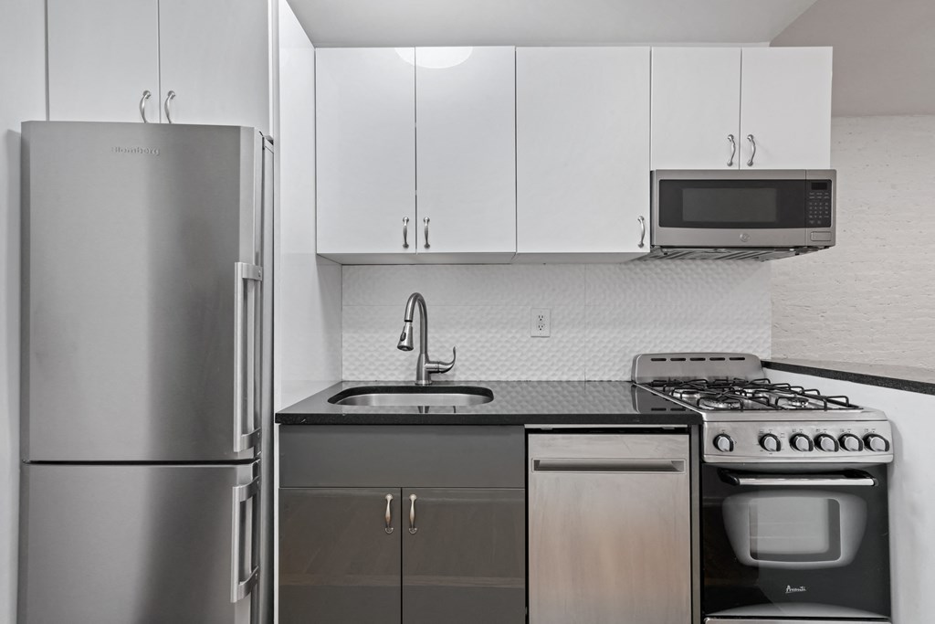 an empty kitchen with stainless steel appliances and white cabinets