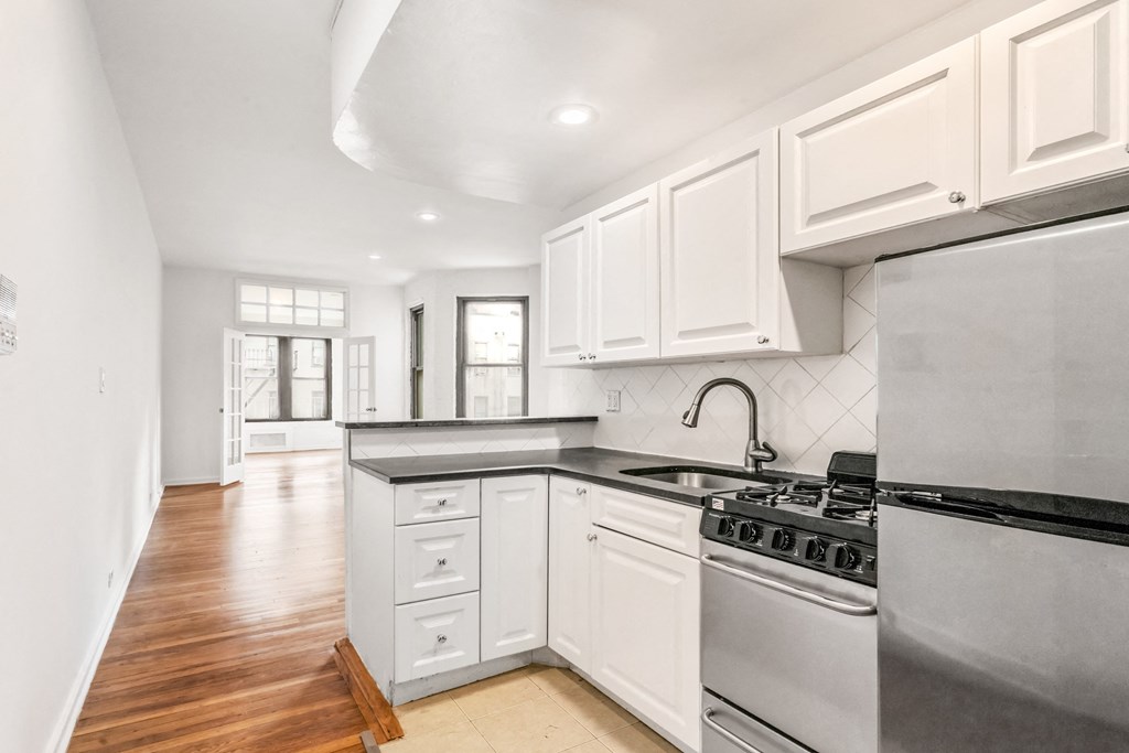 an empty kitchen with white cabinets and stainless steel appliances