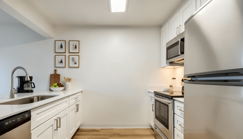 A modern kitchen with white cabinets and stainless steel appliances.