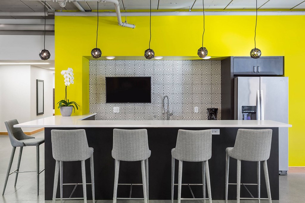 a kitchen with yellow walls and a counter with chairs