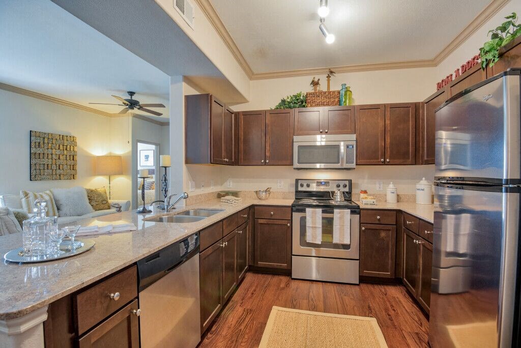 kitchen with stainless steel appliances and wood floor and wood cabinets and marble counter