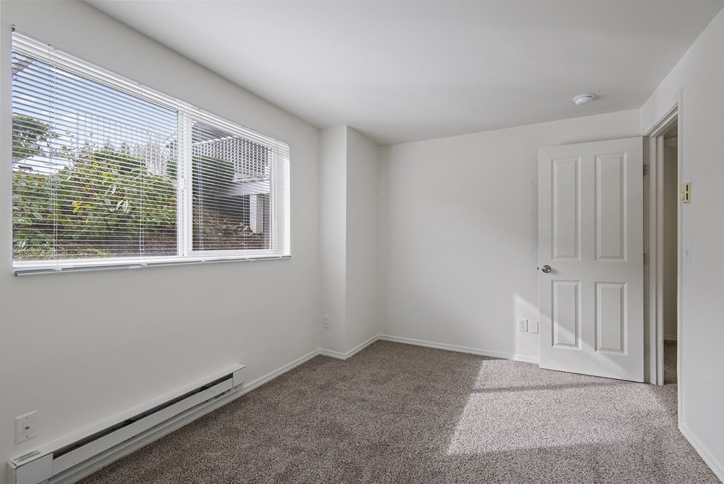 an empty bedroom with a large window and a white door
