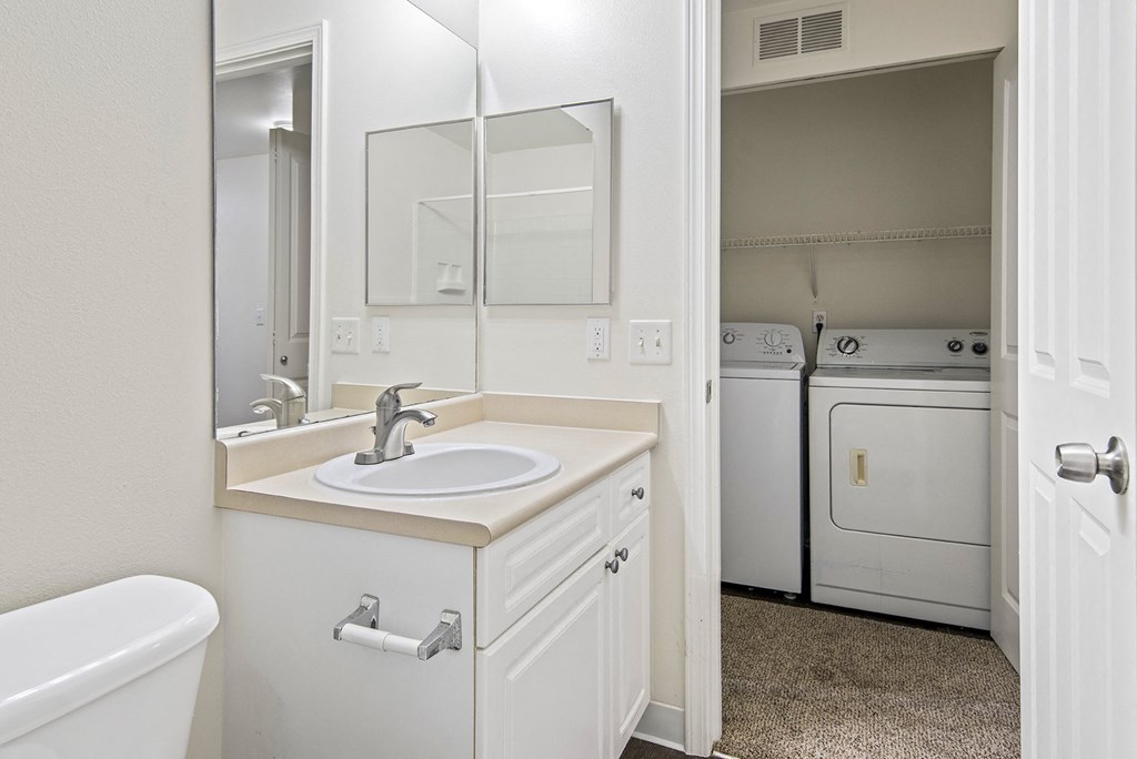 a bathroom with a sink and a mirror and a laundry room