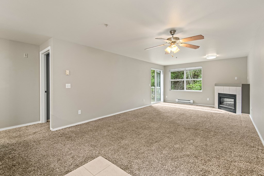 an empty living room with a ceiling fan and a fireplace