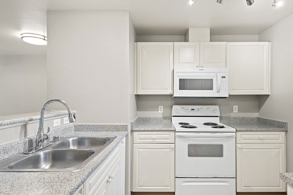 an empty kitchen with white appliances and granite counter tops
