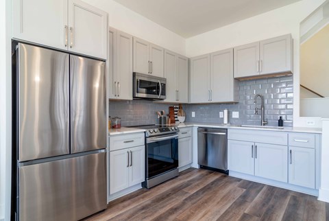 A kitchen with a stainless steel refrigerator and white cabinets.